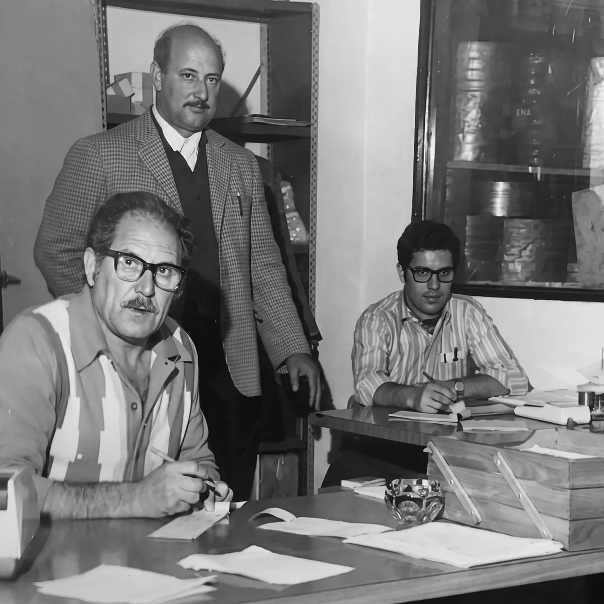 Los fundadores de Ronda reunidos alrededor del escritorio de la oficina de la fábrica